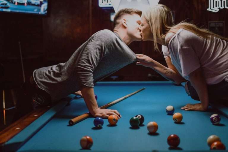 man and woman kissing on pool table